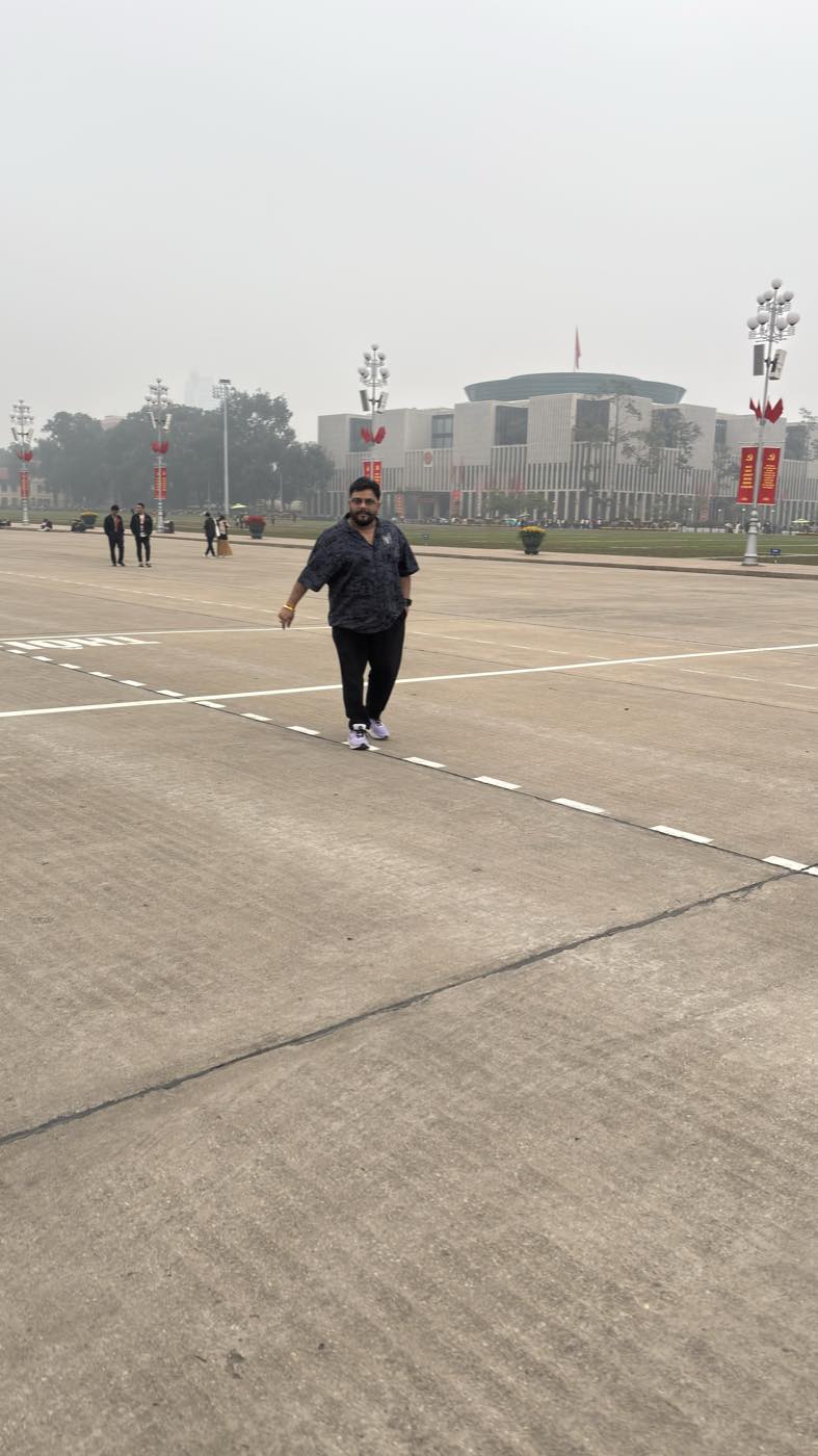 Niraj Choksi walking across a large public square, vertical framing