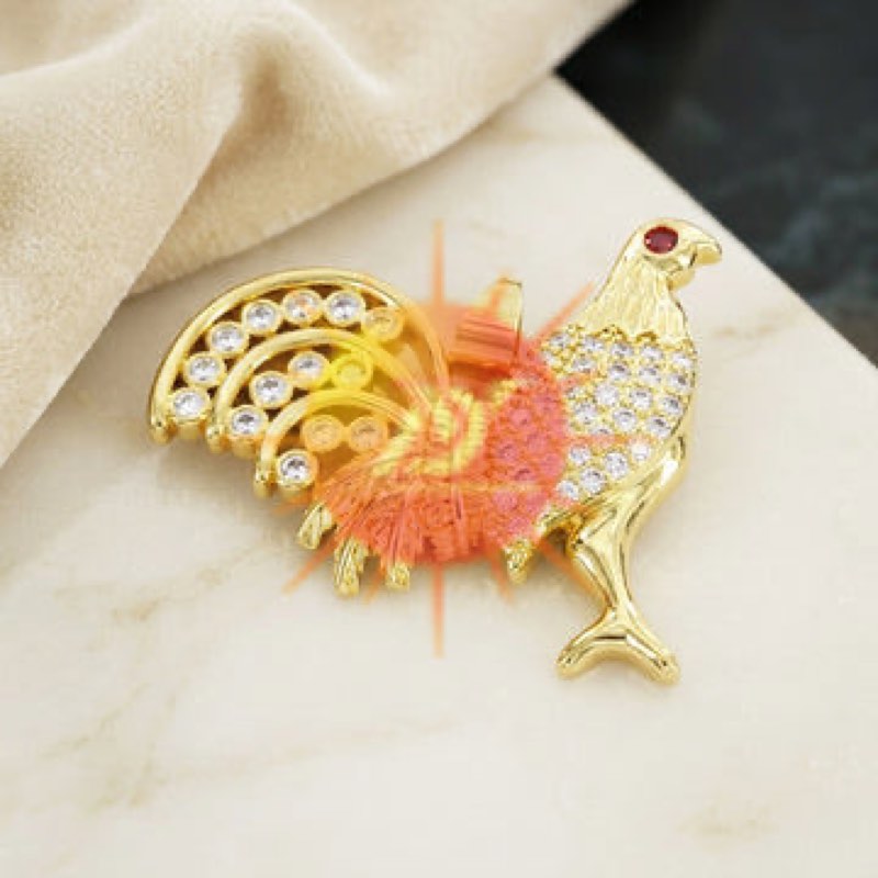 A gold bird brooch set with clear stones, photographed on marble